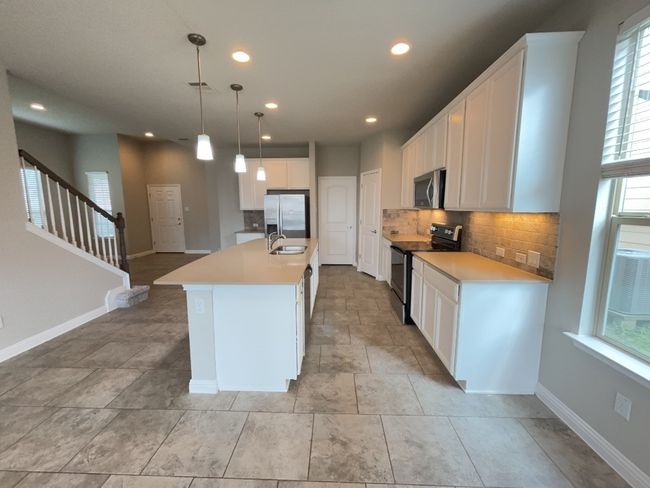Kitchen with stainless steel appliances, tasteful backsplash, healthy amount of natural light, recessed lighting, and white cabinets | Image 8
