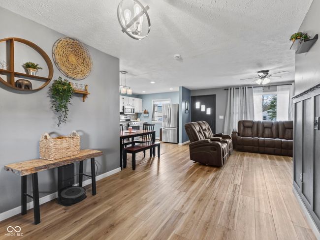 living area with a textured ceiling, baseboards, light wood finished floors, and ceiling fan | Image 17