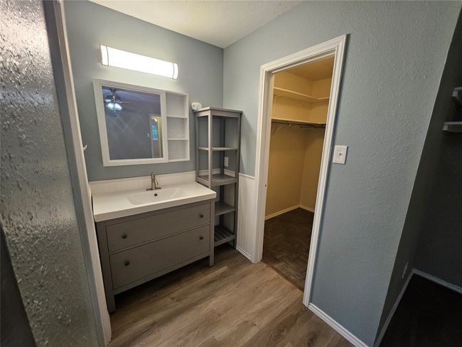 Bathroom with wood finished floors, a walk in closet, ceiling fan, a textured wall, and vanity | Image 23