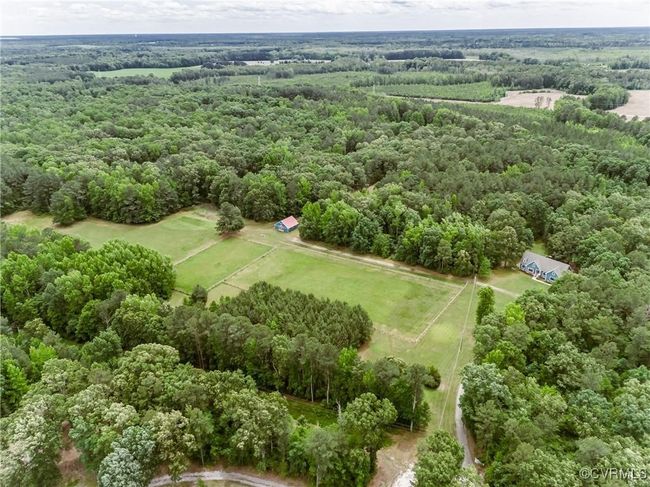 Aerial view of sparsely populated area featuring a heavily wooded area | Image 6