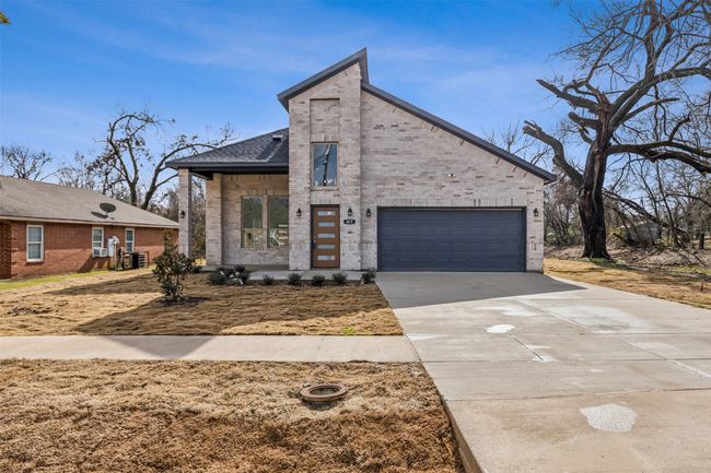 View of front facade with brick siding, concrete driveway, a garage, and a shingled roof | Image 7