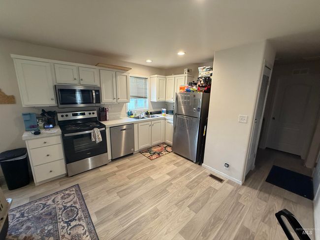 Kitchen with appliances with stainless steel finishes, light countertops, light wood-style flooring, recessed lighting, and white cabinetry | Image 6