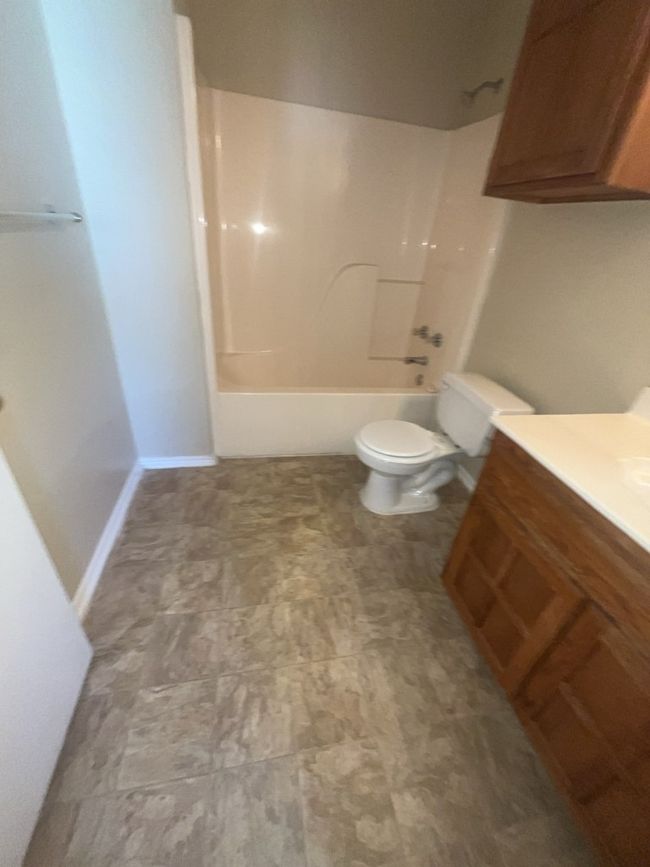 Bathroom featuring bathtub / shower combination, toilet, and vanity | Image 6