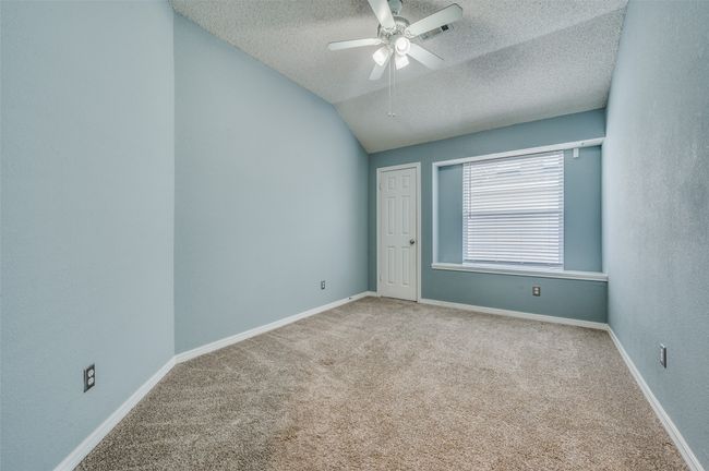 Empty room with a textured ceiling, carpet flooring, a ceiling fan, and vaulted ceiling | Image 16