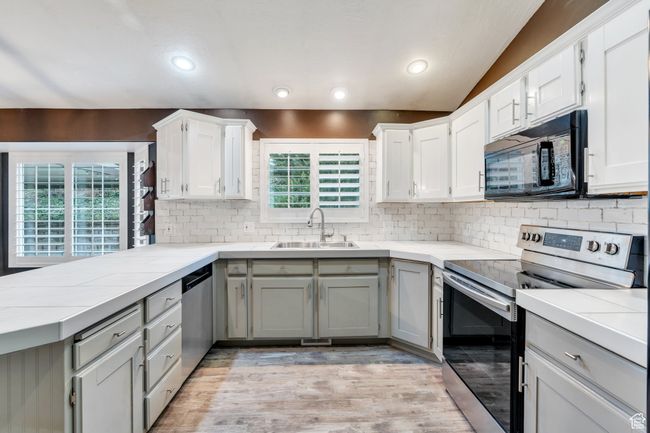 Kitchen featuring a peninsula, a sink, decorative backsplash, light countertops, and appliances with stainless steel finishes | Image 7