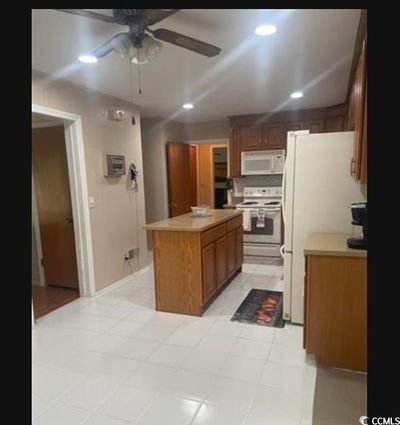 Kitchen with white appliances, a center island, and ceiling fan | Image 2