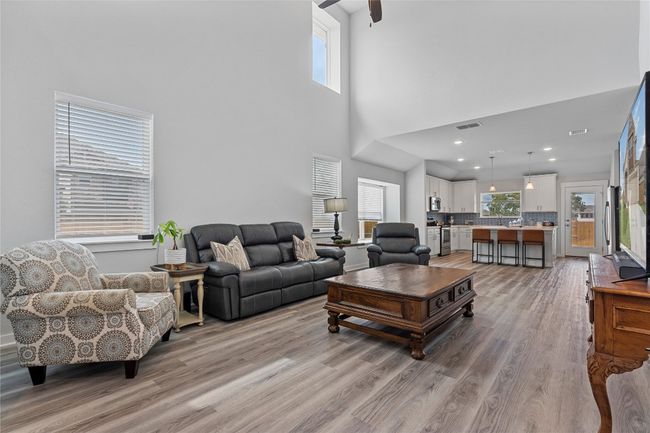 Living room featuring light wood finished floors, plenty of natural light, a high ceiling, and a ceiling fan | Image 7