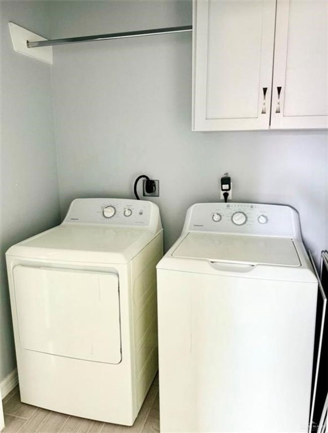 Washroom with light wood finished floors, separate washer and dryer, and cabinet space | Image 10