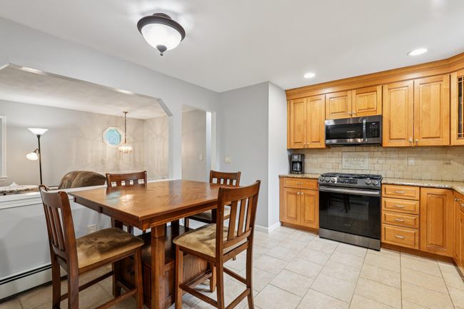 Kitchen with appliances with stainless steel finishes, a baseboard heating unit, tasteful backsplash, light stone counters, and recessed lighting | Image 8