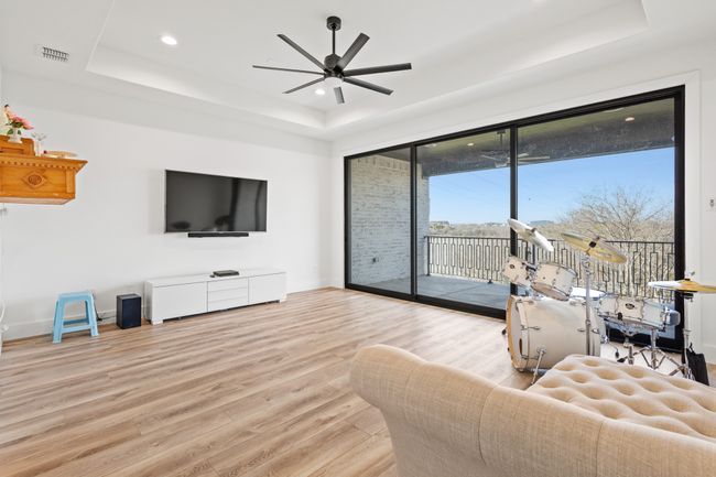 Living area with a raised ceiling, wood finished floors, ceiling fan, recessed lighting, and plenty of natural light | Image 28