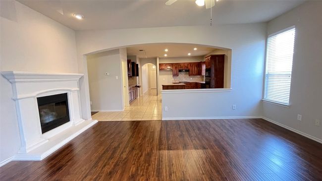 Unfurnished living room with light wood-type flooring, a ceiling fan, a glass covered fireplace, recessed lighting, and arched walkways | Image 15