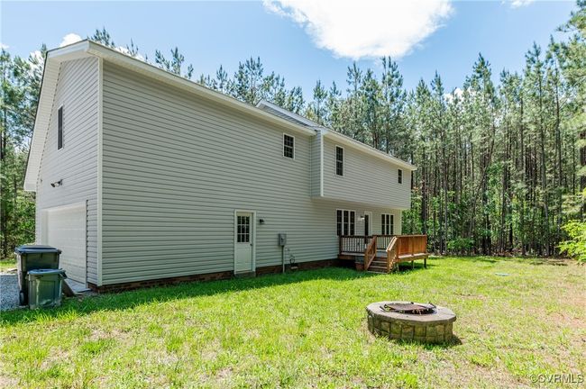 Rear view of property with a fire pit, a garage, a wooden deck, and a lawn | Image 28