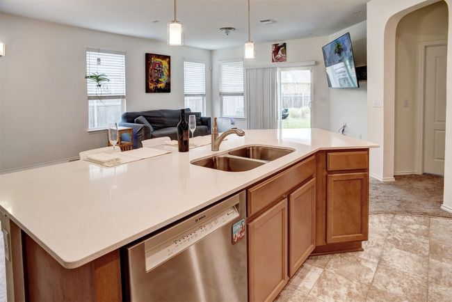 Kitchen featuring dishwasher, light countertops, open floor plan, and decorative light fixtures | Image 21