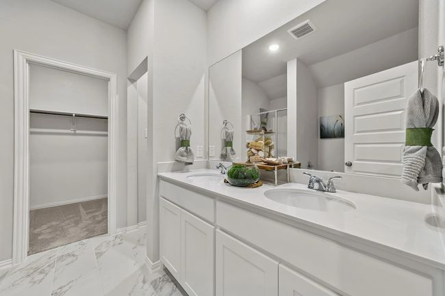 Bathroom featuring double vanity, marble look tile flooring, a walk in closet, a stall shower, and baseboards | Image 22