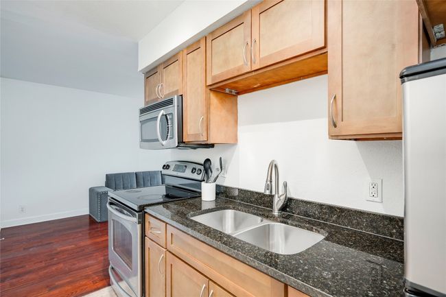 Kitchen featuring stainless steel appliances, a sink, dark stone countertops, dark wood-style floors, and light brown cabinetry | Image 15