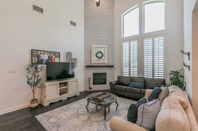 Living room featuring a high ceiling, a fireplace, and dark wood-type flooring | Image 11