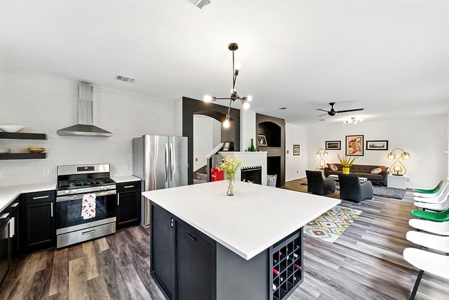 Kitchen featuring light countertops, open shelves, a sink, and a center island | Image 9