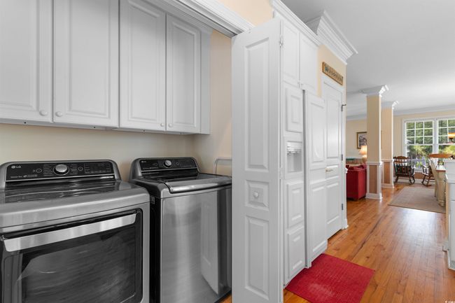 Washroom with light wood-type flooring, washer and dryer, decorative columns, and crown molding | Image 29