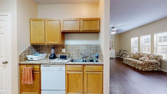 Kitchen with a sink, white dishwasher, ceiling fan, and decorative backsplash | Image 9