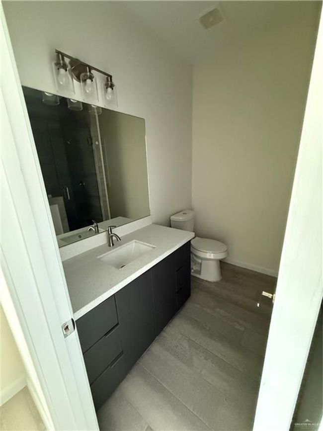 Bathroom featuring vanity, toilet, wood finished floors, a shower stall, and baseboards | Image 10