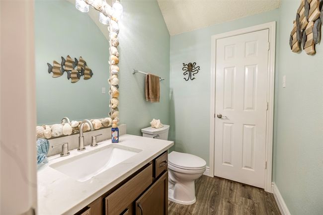 Half bathroom with toilet, vanity, wood finished floors, and lofted ceiling | Image 9