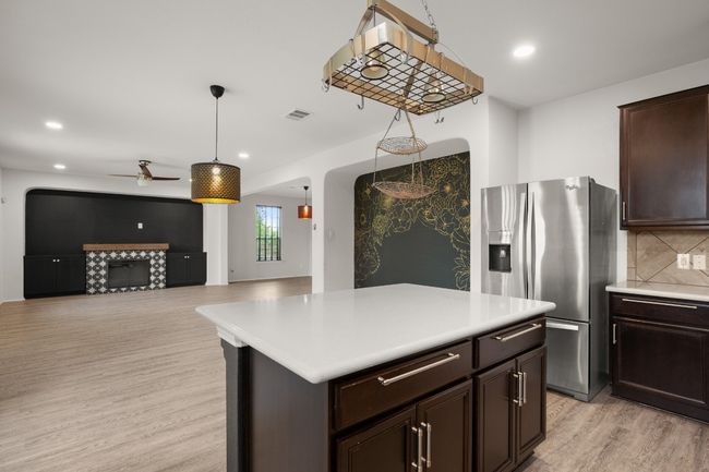 Kitchen featuring light countertops, a ceiling fan, light wood finished floors, and stainless steel fridge with ice dispenser | Image 23