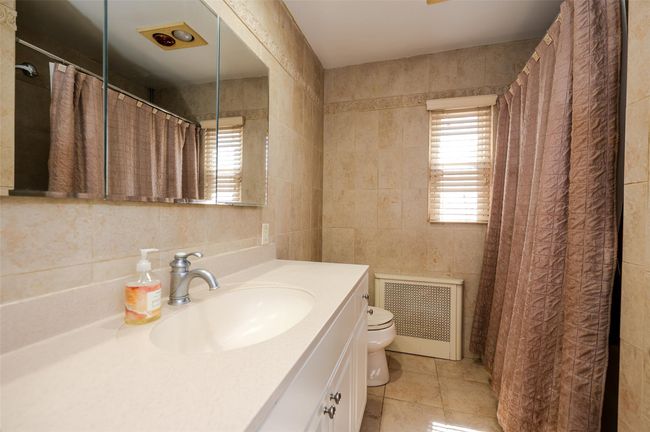 Full bath with vanity, tile walls, toilet, tile patterned floors, and visible vents | Image 16