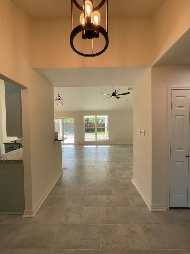 Entry featuring a high ceiling, tile patterned floors, baseboards, and an inviting chandelier | Image 6