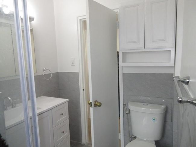 Bathroom featuring tile walls, wainscoting, vanity, and toilet | Image 9
