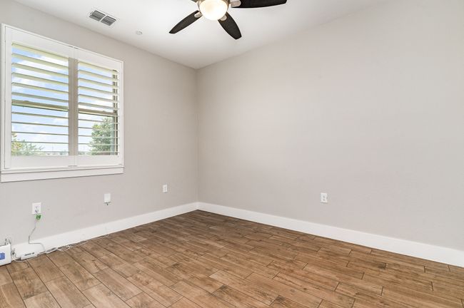 Secondary bedroom featuring ceiling fan, wood finished floors, and baseboards | Image 23