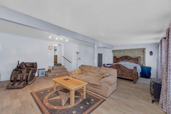 Living room with light wood-style flooring, stairs, and a wood stove | Image 16