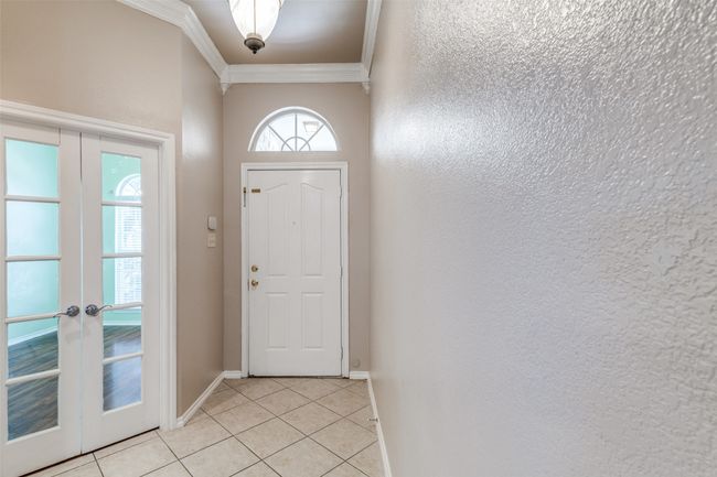 Doorway featuring ornamental molding, light tile patterned floors, french doors, and a textured wall | Image 4
