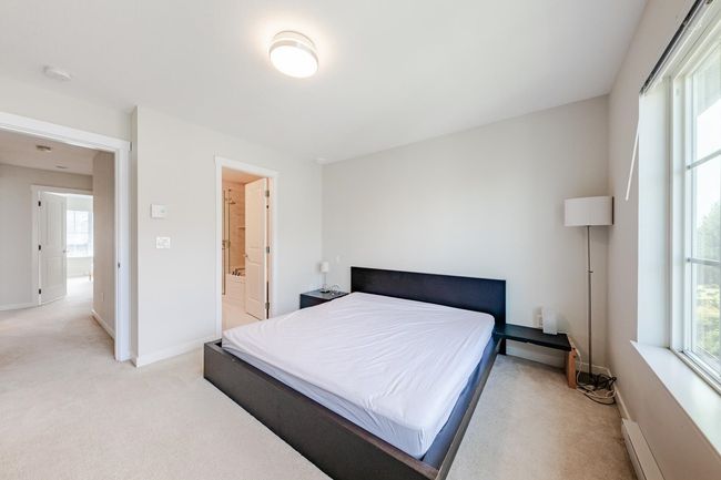 Bedroom featuring light colored carpet, a baseboard heating unit, and connected bathroom | Image 17