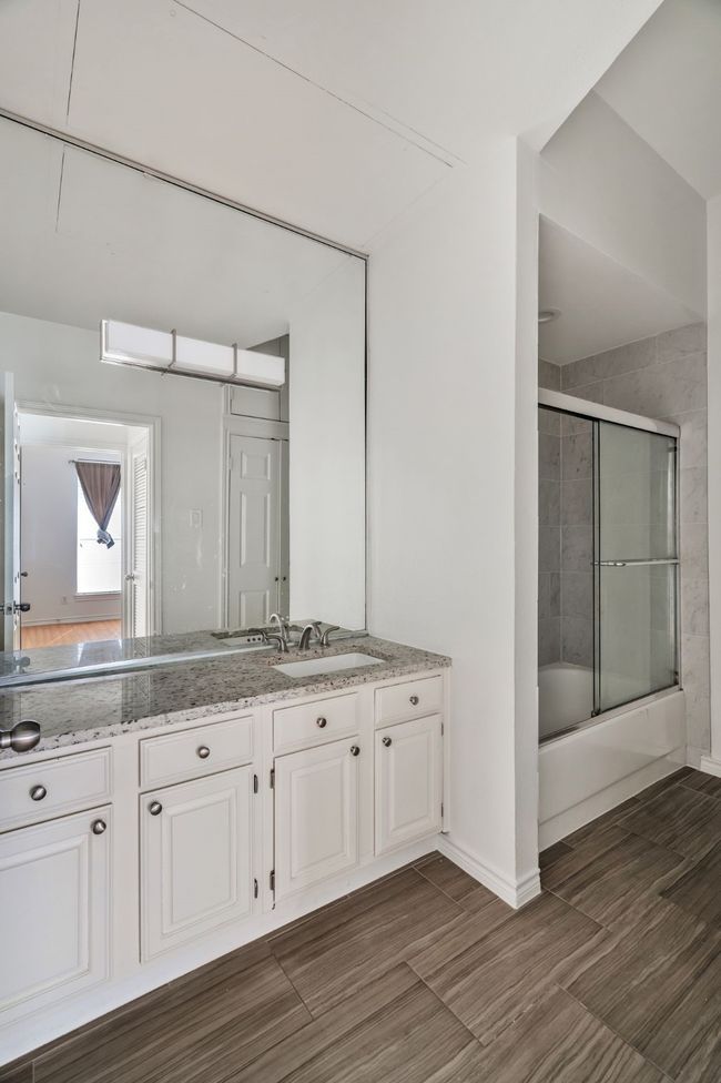 Bathroom with enclosed tub / shower combo, baseboards, vanity, and wood finished floors | Image 8
