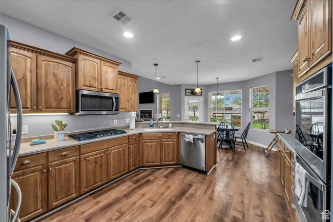 Kitchen with visible vents, a sink, dark wood-type flooring, a peninsula, and appliances with stainless steel finishes | Image 17