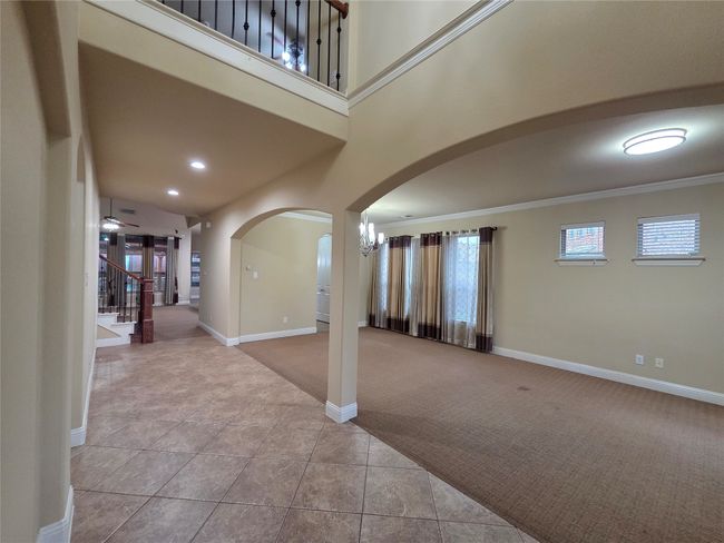 Carpeted entrance foyer featuring arched walkways, stairs, ornamental molding, tile patterned floors, and recessed lighting | Image 10