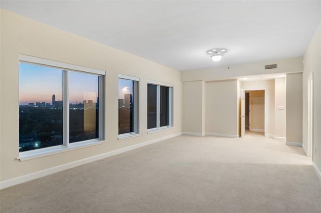 Spacious primary bedroom with expansive windows offering stunning skyline views. | Image 24