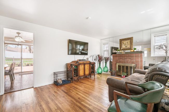 Living room featuring plenty of natural light, a brick fireplace, wood finished floors, and ceiling fan | Image 5