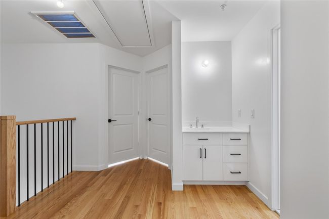 Hall with light wood finished floors, attic access, a sink, baseboards, and visible vents | Image 33