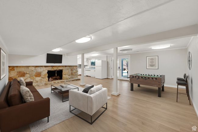 Living room featuring light wood finished floors, baseboards, a fireplace, and crown molding | Image 19