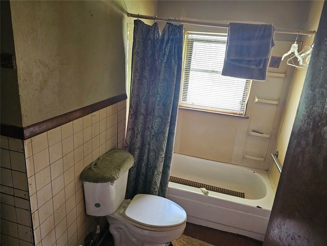 Bathroom with tile walls, shower / tub combo, and wainscoting | Image 6