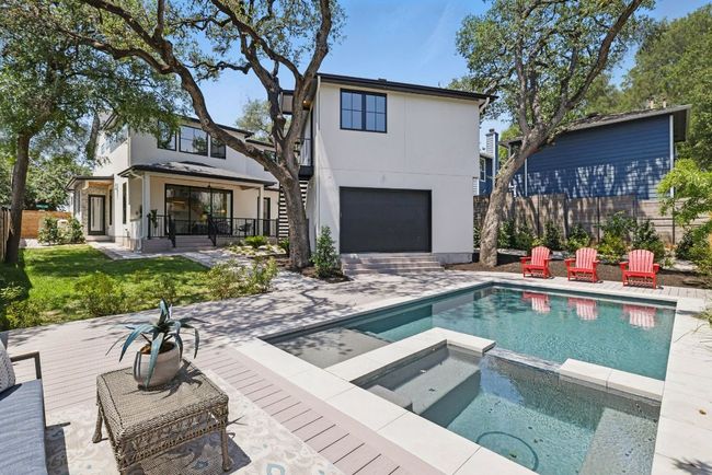 Rear view of house with a pool with connected hot tub, stucco siding, fence, and a garage | Image 35