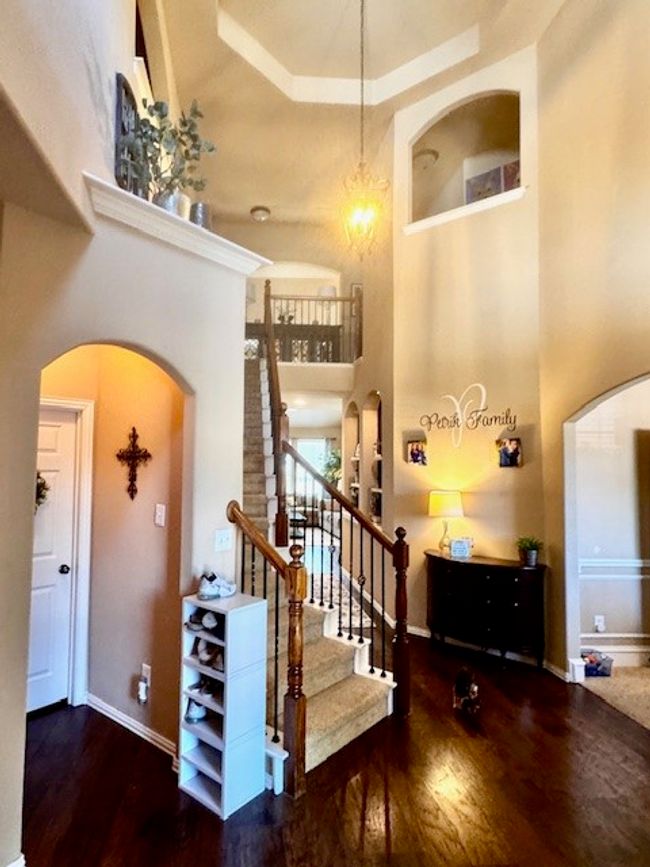 Stairs featuring baseboards, wood finished floors, arched walkways, and a towering ceiling | Image 10