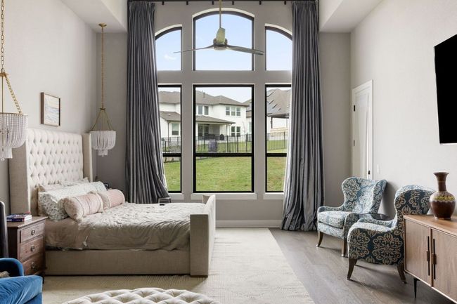 Bedroom featuring light wood finished floors, a towering ceiling, and multiple windows | Image 15