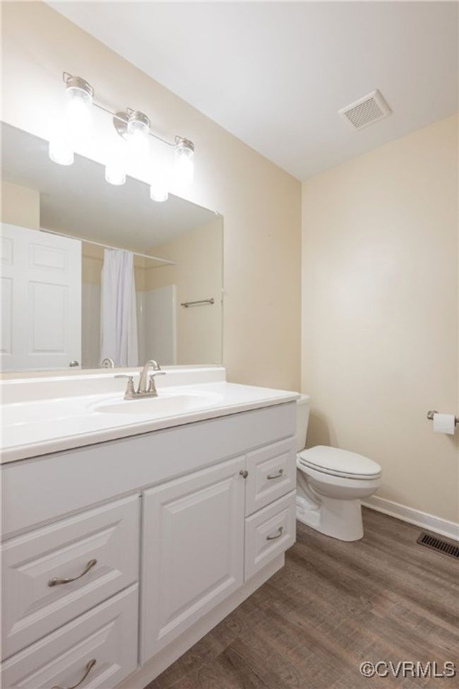 Full bath featuring vanity, toilet, visible vents, curtained shower, and wood finished floors | Image 23