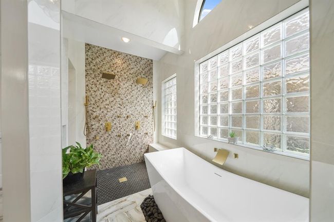 Relax and unwind in the floor-to-ceiling custom tiled shower with dual shower heads, multiple body sprays, dual handheld shower wands & seating. | Image 23