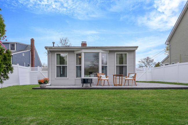 Back of property with a fenced backyard, a gate, a chimney, a lawn, and a deck | Image 13