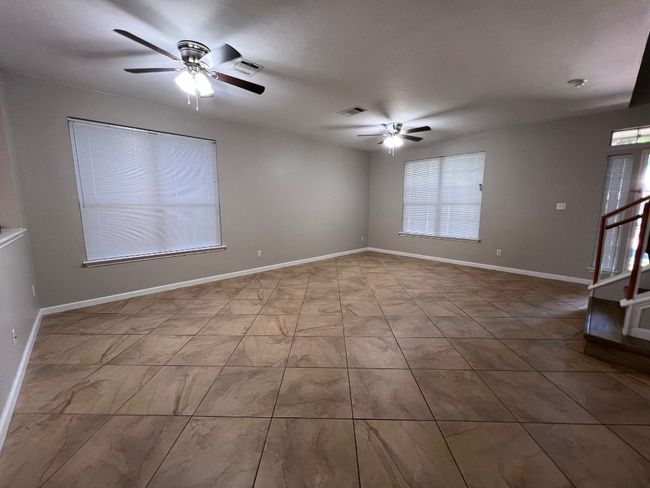 Unfurnished room with a ceiling fan, stairway, and baseboards | Image 5