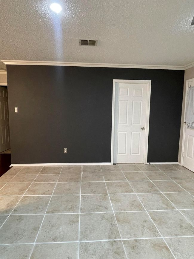 Empty room featuring crown molding, a textured ceiling, and tile patterned floors | Image 14