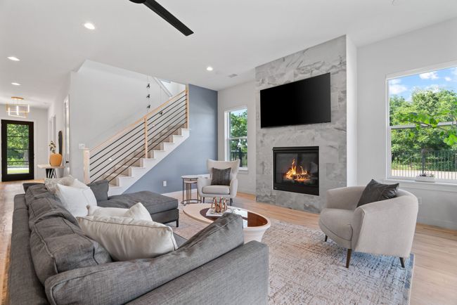 Living area featuring stairway, light wood-type flooring, recessed lighting, a high end fireplace, and a ceiling fan | Image 9